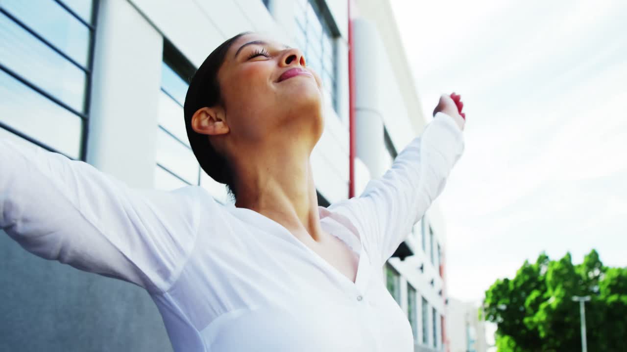 mujer al aire libre levantando los brazos en alegría con el fondo de la construcción