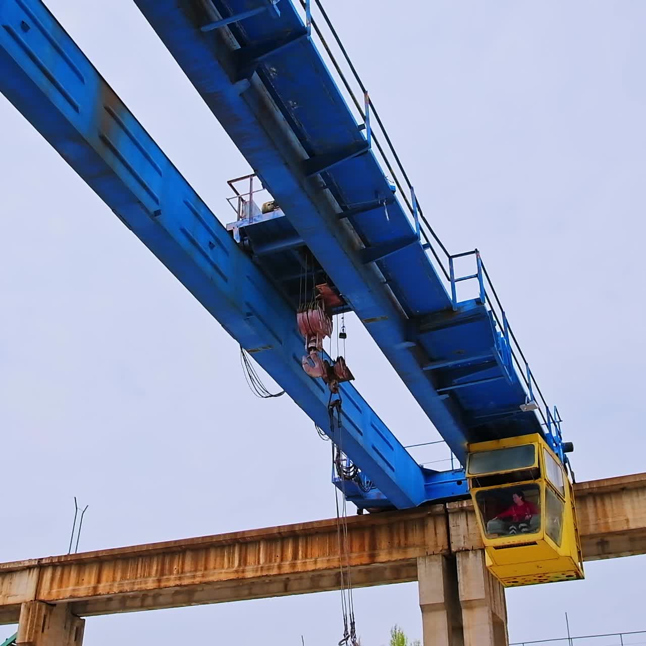 Blue massive metal supports on the height with crane mechanism. Machine for transporting heavy weights at construction building