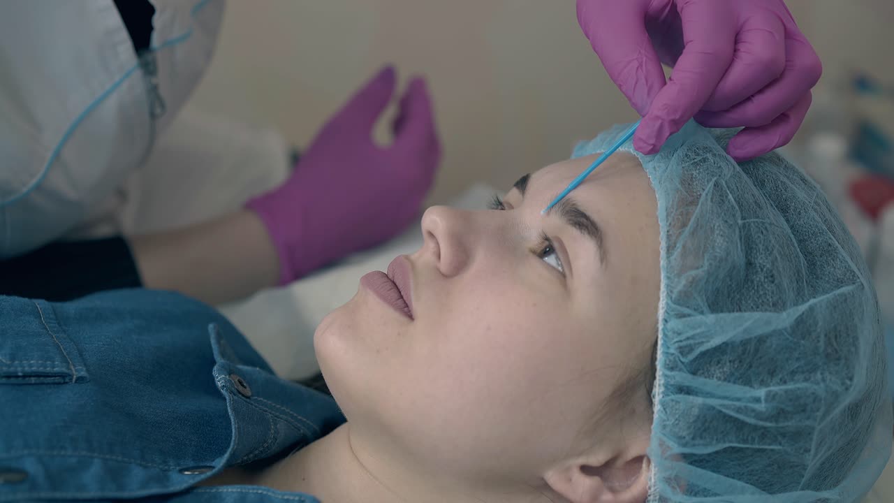 el cliente se acuesta en el sofá durante el examen de las cejas del cosmetólogo