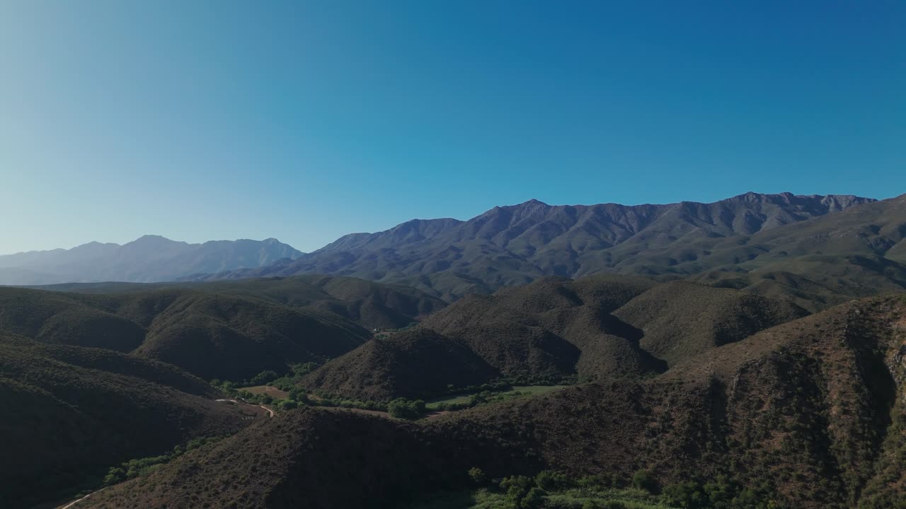Aerial shot of the Klein Karoo mountain range, Western Cape, South Africa, on a sunny day. The drone captures multiple layers of rugged mountain peaks, creating a stunning, expansive landscap