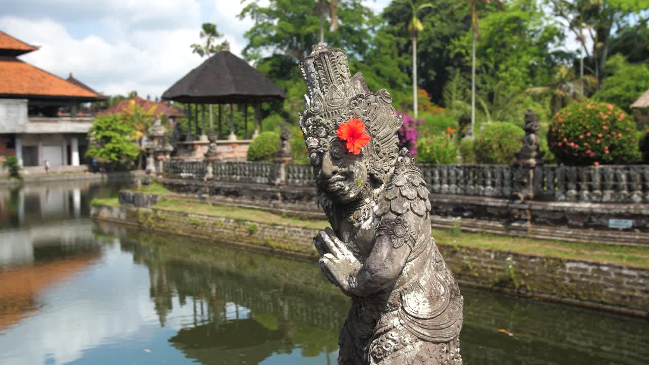 Panorâmica com foco seletivo de uma estátua na entrada do Templo Taman Ayun, Regência de Badung, Bali, Indonésia.
