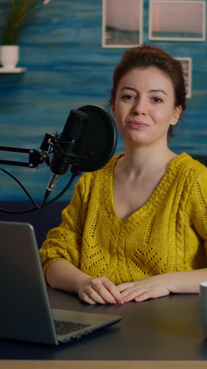 Video verticale: Ritratto di giovane vlogger che lavora in uno studio accogliente, sorridendo alla telecamera
