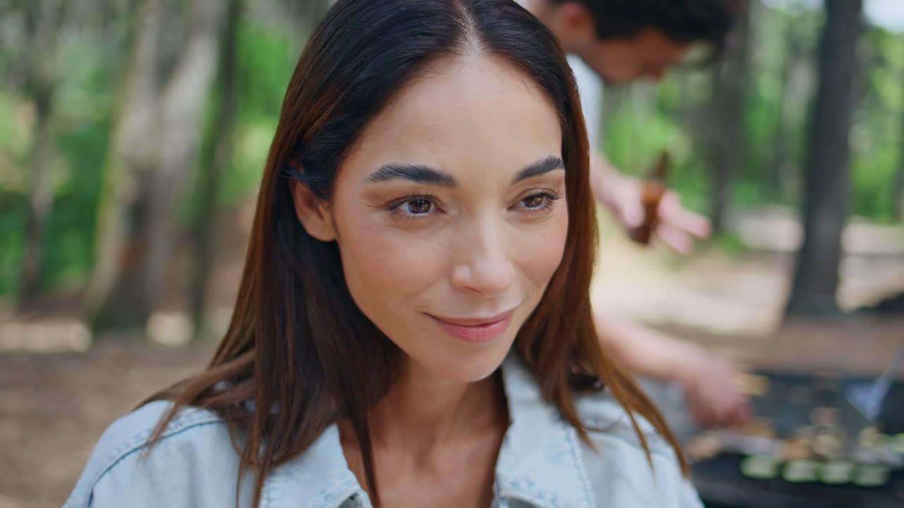 People cooking barbeque meal on grill while woman talking with friend in closeup