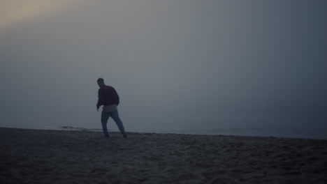 thoughtful guy looking sea landscape at misty morning. man walking on beach