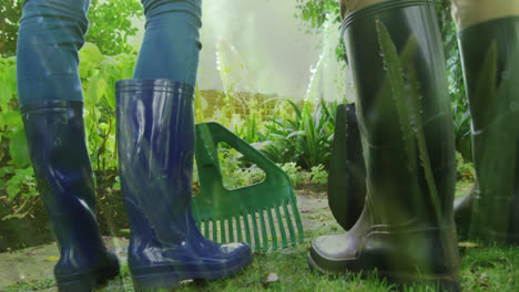 animation of grass over legs of two people wearing rubber boots working in garden