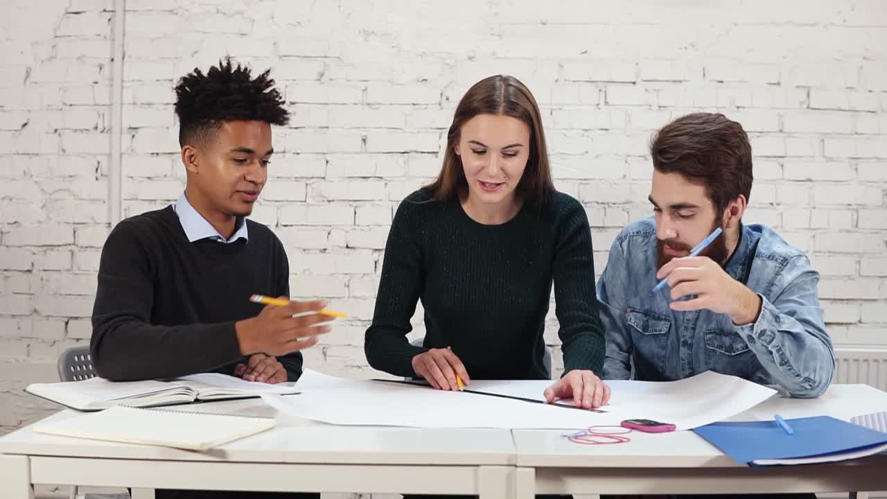 Group of young interior designers team working together in creative office. Young professionals making sketches sitting at the