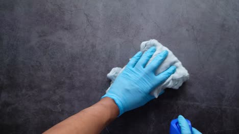 cleaning a countertop with gloves and spray bottle