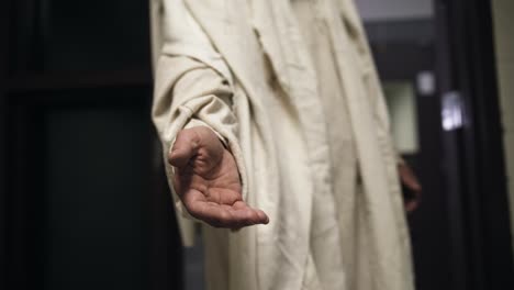 jesus wearing a white robe extends his hand to a prisoner in his cell