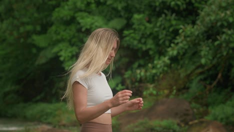 Attractive-woman-in-jungle-taking-fresh-water-from-river-splashing-on-face