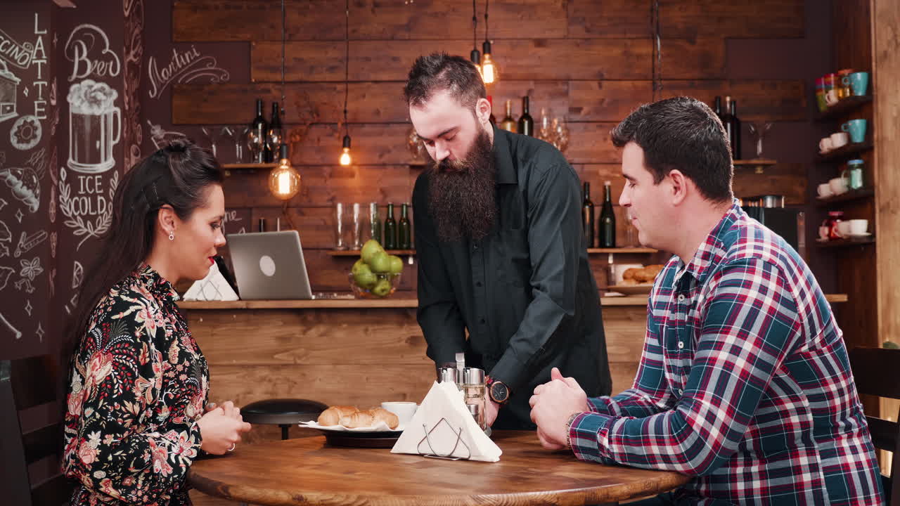 A waiter serving a couple in a restaurant