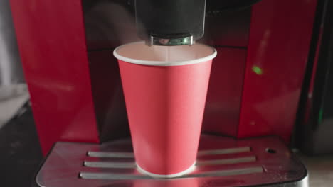 coffee machine dispensing espresso into red paper cup, close-up of brewing process, hot beverage preparation in modern cafe setting, steaming espresso shot flowing smoothly, perfect for coffee related scenes