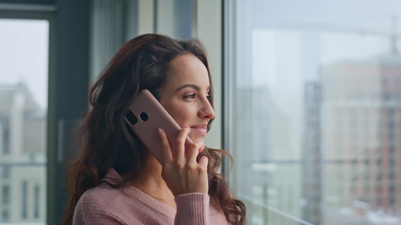 mujer feliz hablando teléfono inteligente moderno apartamento de vidrio primer plano. chica final de la llamada