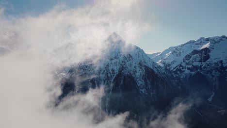 Drone-video-flying-through-the-clouds-towards-a-snowy-mountain-range