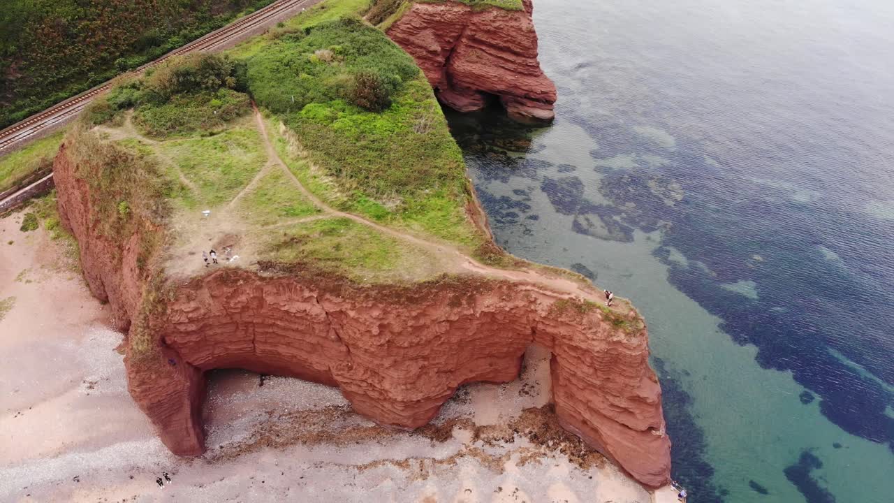 Drone capture of Dawlish's iconic red sandstone cliffs surrounded by scenic ocean views.