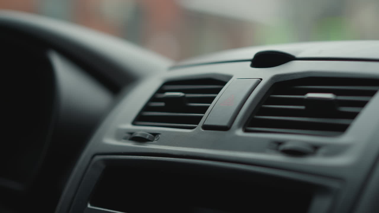 Close up hand view of owner pressing knob on car dashboard console vent control panel under soft cabin lighting highlighting finger gesture and textured plastic trim during winter commute