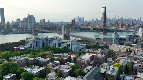 cinematic drone shot over brooklyn heights neighborhood with traffic on brooklyn bridge and manhattan bridge at sunset time - skyline with skyscraper and east river in background, nyc - wide shot