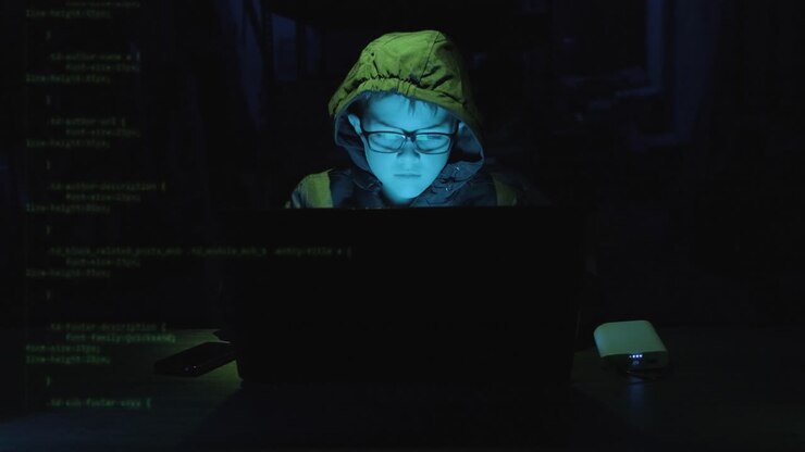 Young Boy Hacker Typing On Laptop With Security Codes Moving In The Screen In A Dark Workplace. - static