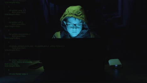 Young Boy Hacker Typing On Laptop With Security Codes Moving In The Screen In A Dark Workplace. - static