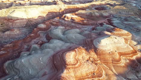 aerial 4k drone flyover view of bentonite hills, utah, at golden hour with colorful mars like landscape