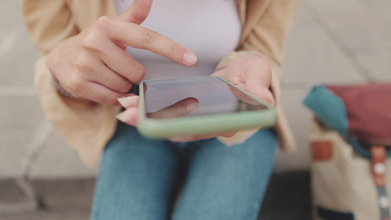 Primo piano di mani che scorrono e usano uno smartphone all'aperto