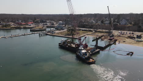 semi-circle aerial footage of barge and tugboat off shore of harbor