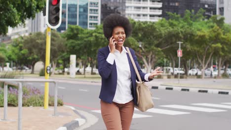 Smiling-african-american-businesswoman-walking-and-talking-on-smartphone