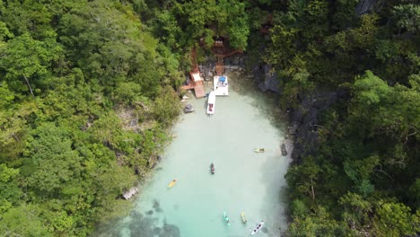 people on vacation kayaking in turquoise clear water of cadlao lagoon, el nido, aerial