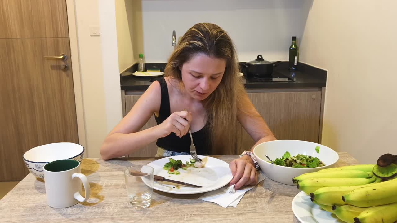 Woman Eating Salad with Bananas in the Kitchen