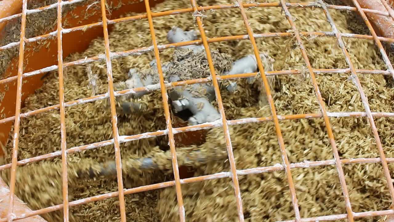 Lähikuva toiminnassa olevasta hamppubetonisekoittimesta ristikon läpi kuvattuna.