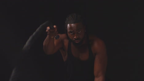 Studio-Shot-Of-Male-Athlete-Training-Wearing-Vest-Using-Battle-Ropes-Shot-Against-Black-Background-2