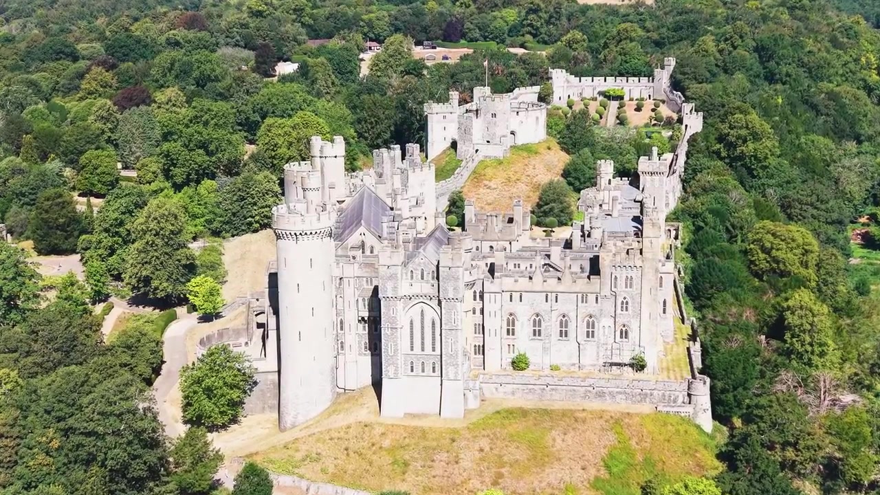 Mouvement de caméra en avant par drone sur le château d'Arundel, la caméra restant fixée sur la forteresse, s'inclinant vers le bas tout en s'approchant au-dessus des cimes des arbres et des terrains aménagés dans le West Sussex, Angleterre.