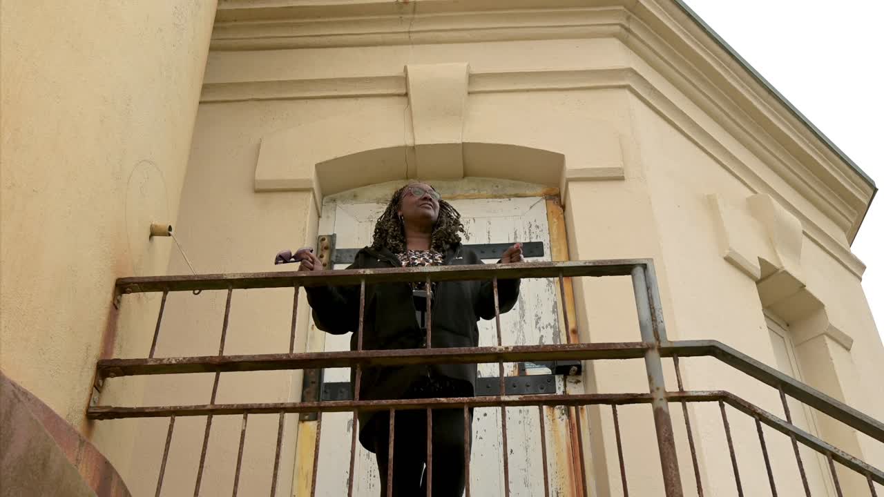 bonita mujer negra retrato de todo el cuerpo con trenzas, ángulo bajo, de pie en el faro, mirando en la distancia