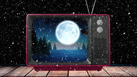 animation of santa claus in sleigh with reindeer on tv at christmas, with snow falling at night