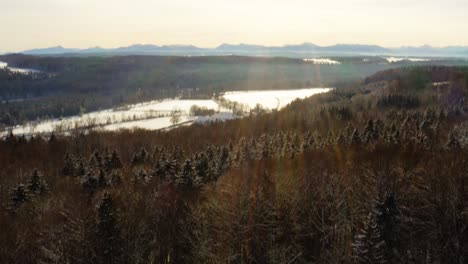 Sunshine-at-a-winter-landscape-drone-view---smooth-flight-over-a-forest-with-the-view-at-a-monastery-on-a-sunny-winter-day