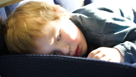 little boy lying on the seat in bus car ot train