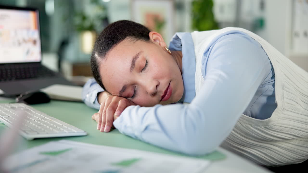 Tired businesswoman sleeping on her desk in the office