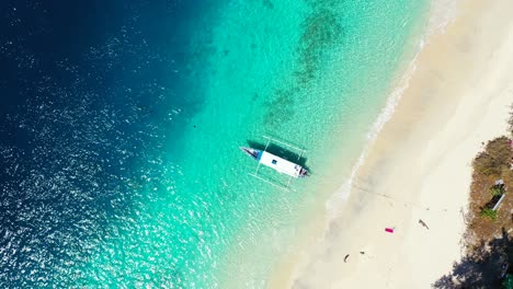 Draufsicht-Auf-Die-Wunderschöne-Landschaft-Eines-Touristischen-Segelboots,-Das-Im-Grünen-Meer-Mit-Weißem-Sand-Schwimmt---Luftaufnahme