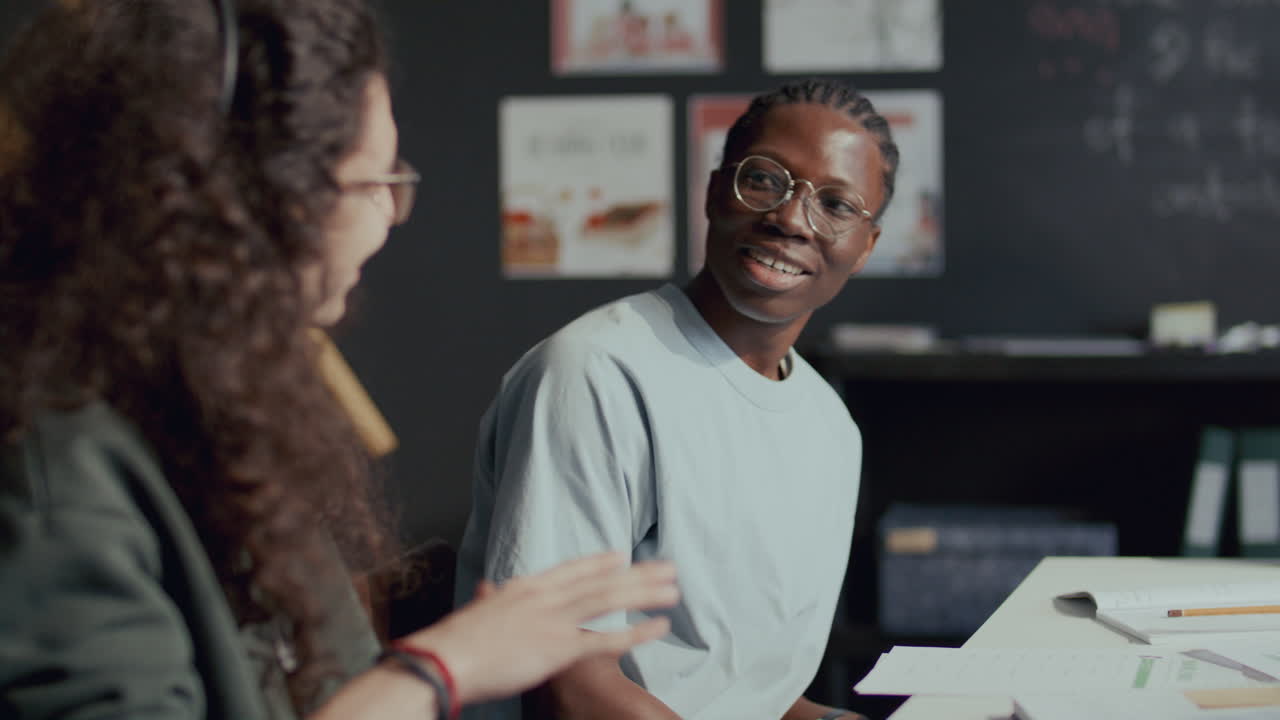 Young Black Student Discussing Assignment with Classmate during English Lesson