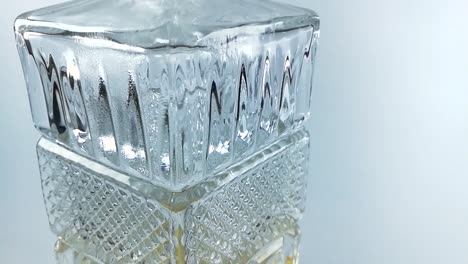 beautiful crystal glass bottle with a little whiskey in it on a white background, tilt down