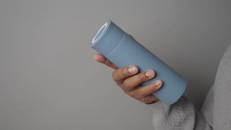 person holding a light blue thermos