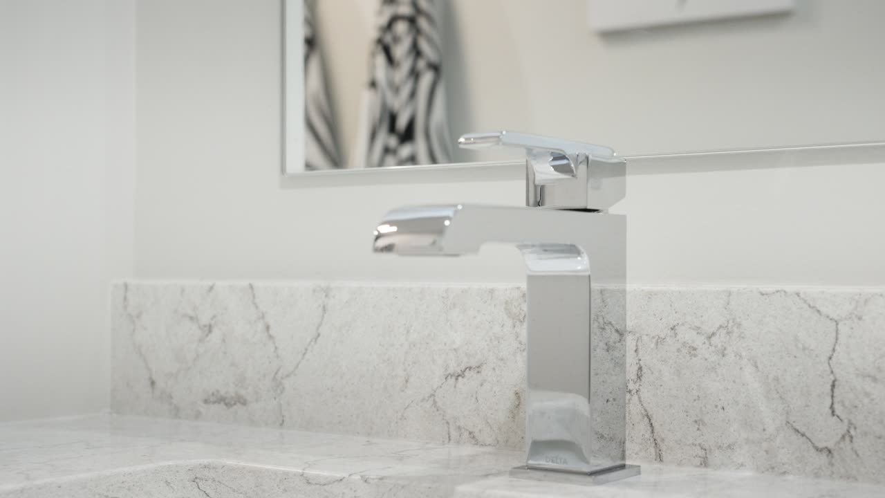 Primo piano di un rubinetto da bagno cromato moderno con acqua corrente