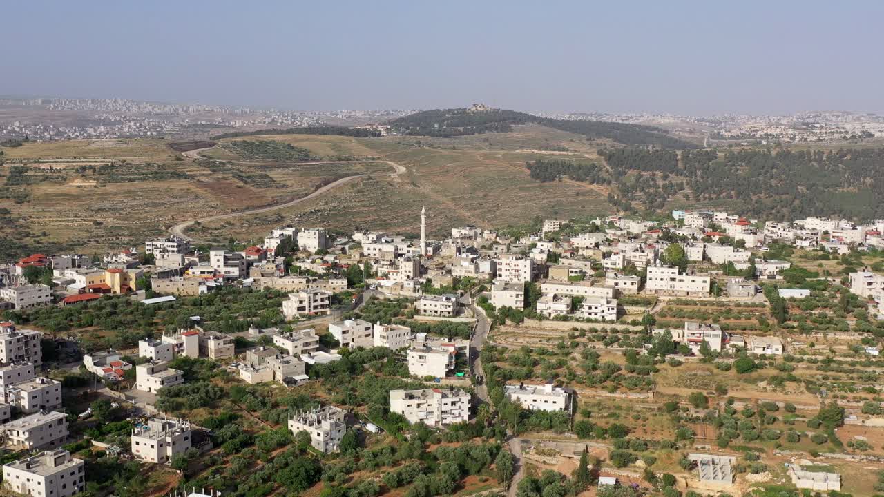 Aerial View of a Middle Eastern Village with a Minaret and Olive Groves in a Hilly Landscape