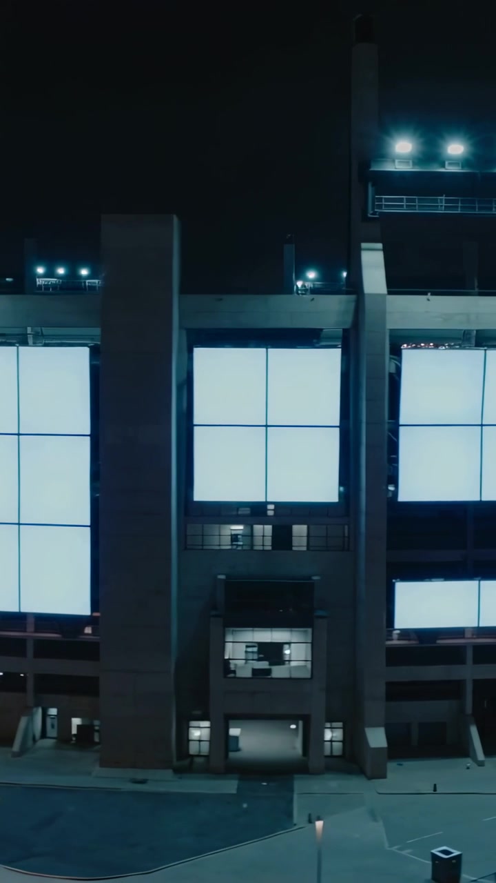 Video verticale: Telecamera che esegue una panoramica a destra sulla facciata dell'arena di notte, rivelando pannelli LED e colonne