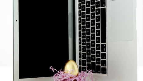 golden easter egg and laptop on white background