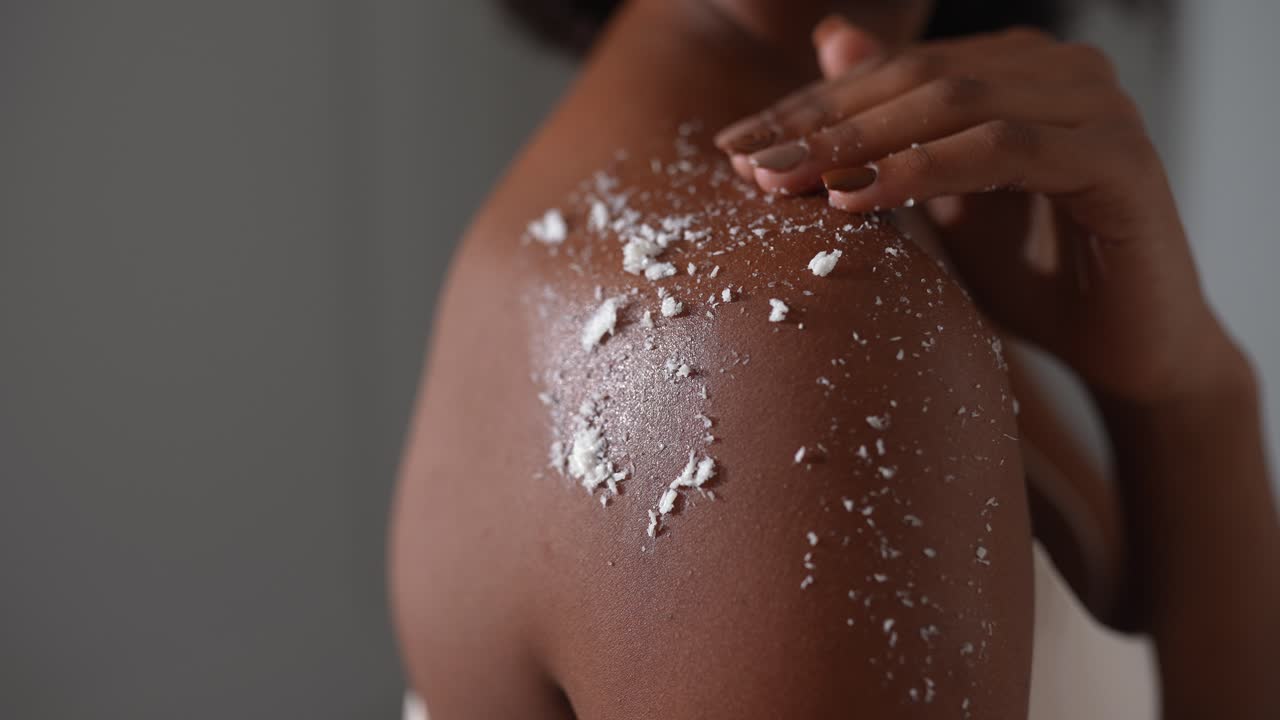 mujer aplicando exfoliante corporal al hombro