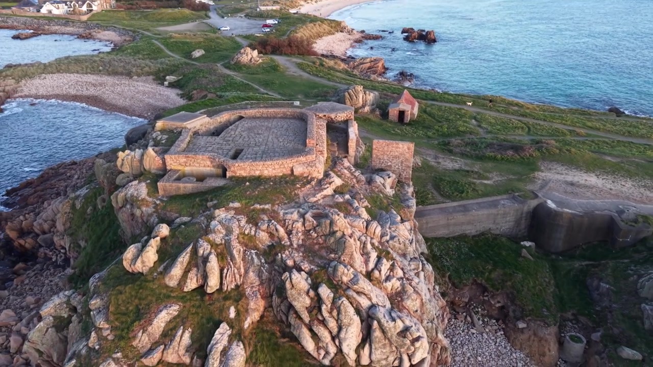 Grandes Rocques Guernsey Isole del Canale. Volo a bassa quota all'ora d'oro sopra un vecchio forte militare arroccato su rocce tra tre baie, vicino al tramonto sulla costa occidentale.