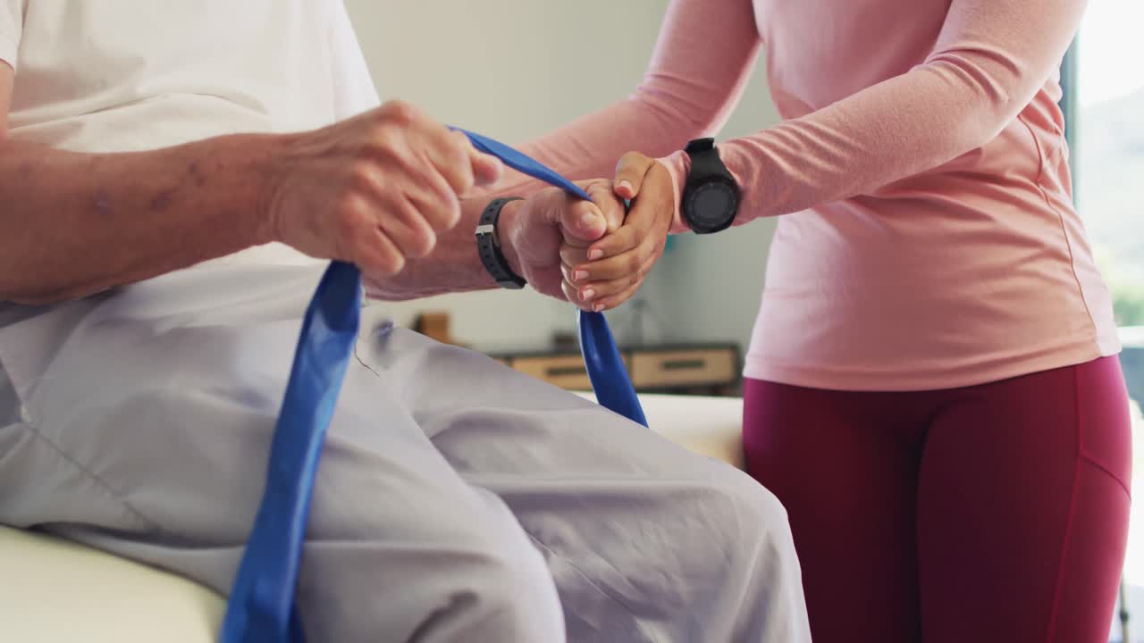 행복한 두 인종 여성 물리 치료사가 백인 노인과 함께 운동하는 중간 섹션의 비디오