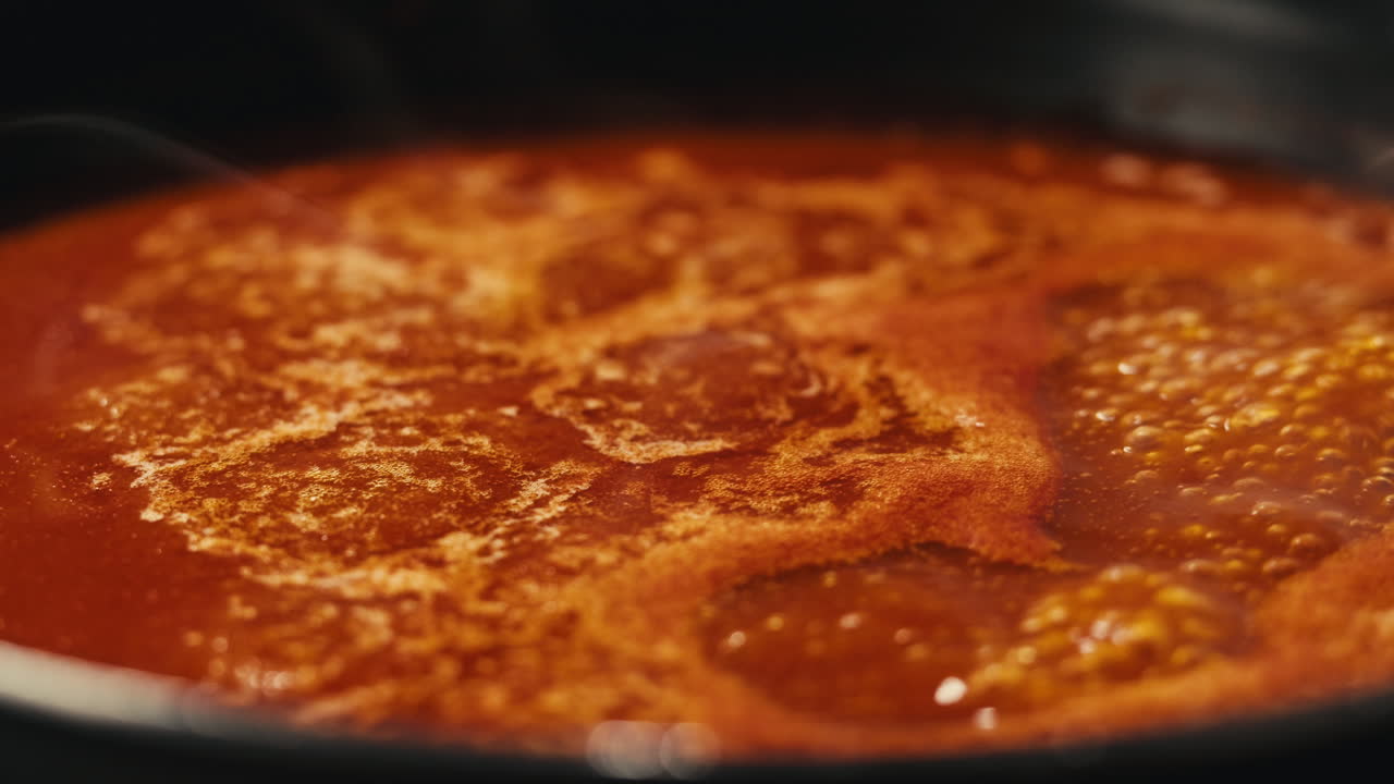 Chicken in tomato sauce is boiling on a frying pan with spices. Cooking tomato sauce curry with chicken fillet. Traditional Italian Mexican Asian dish. High quality studio shot for cafe, restaurant close up.