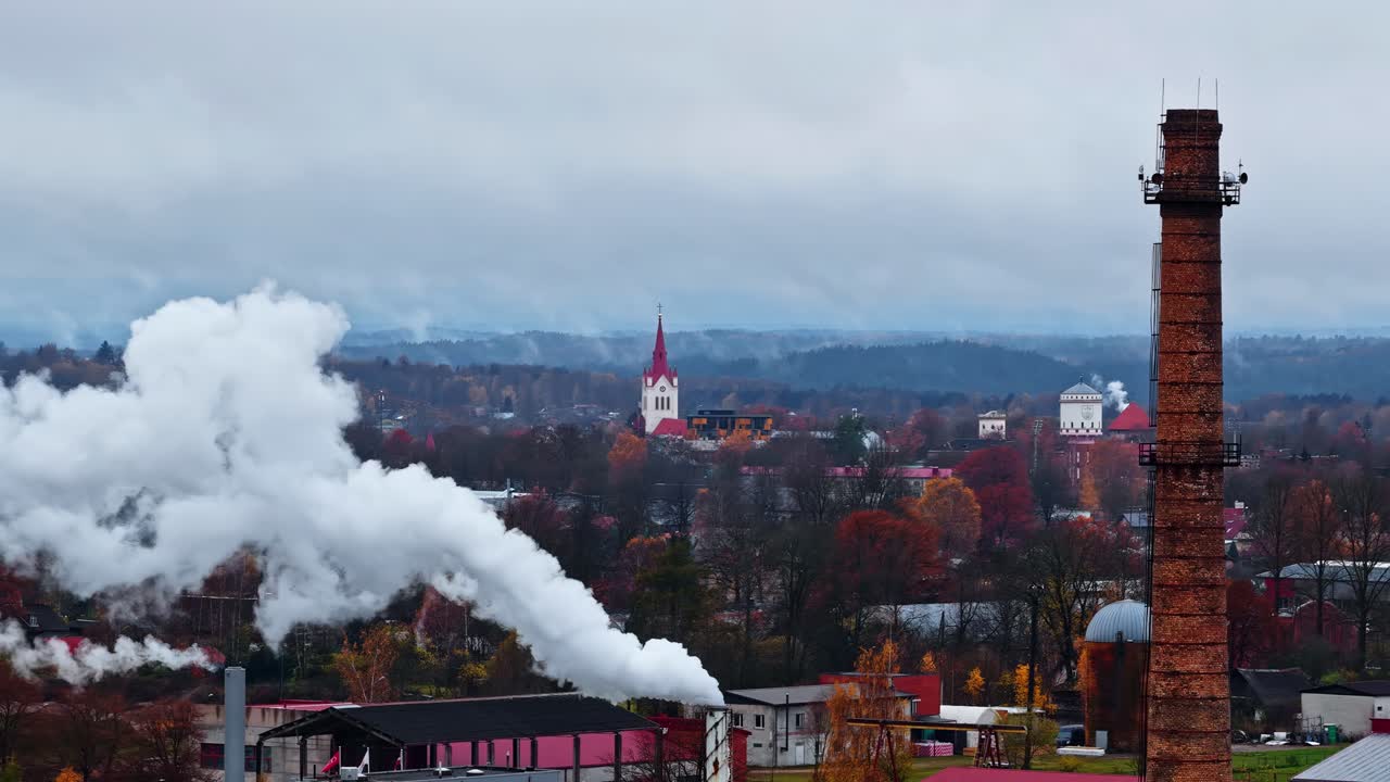 Cēsis, Latvia - Steam Rises Beside a Tall Chimney, Framing the Autumn Landscape and Distant Church Tower - Aerial Drone Shot