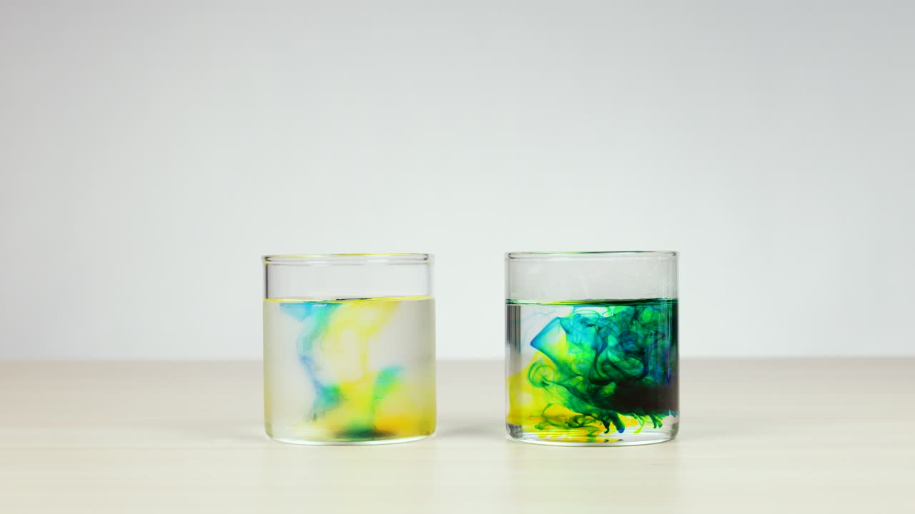 Yellow and green food coloring disperses differently in two glasses of hot and cold water